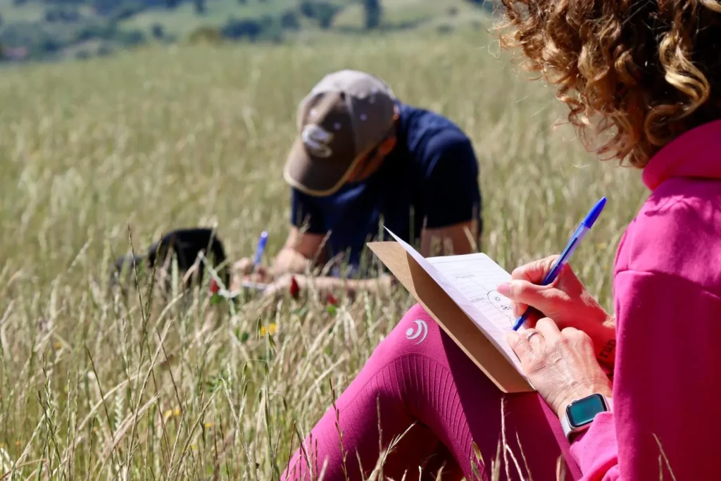 Donna che scrive in mezzo alla naturae che lavora sulla propria crescita personale
